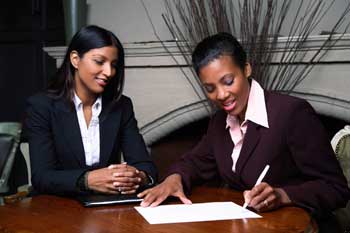 Two business women signing contracts