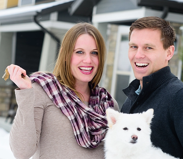 a couple and their dog with house keys in woman's hand
