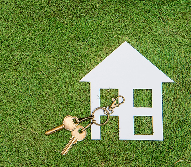 house cutout laying in grass with house keys 
