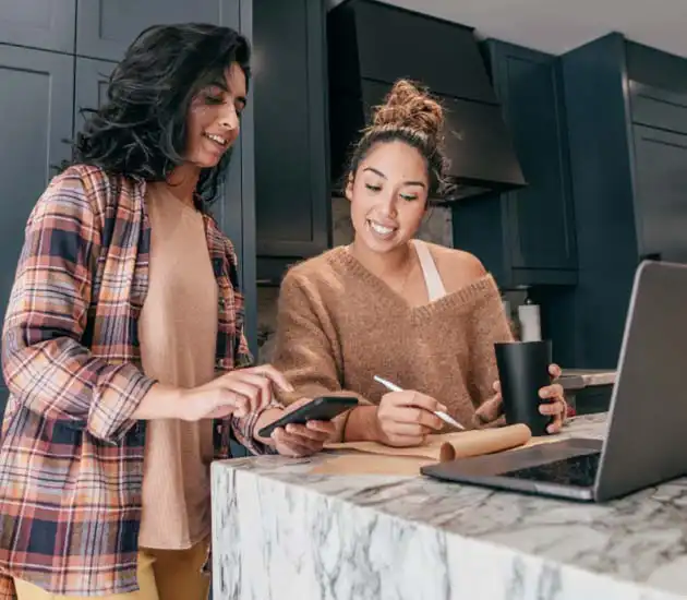 two women in the kitchen looking at a laptop
