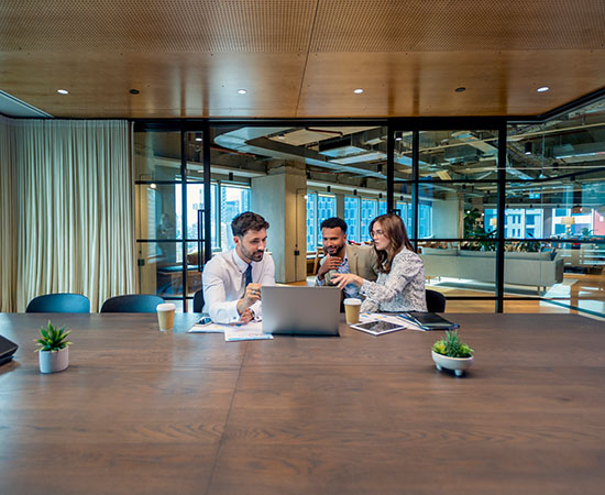three people in a large wood panelled boardroom