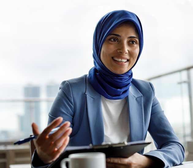 Portrait of confident young Middle Eastern woman smiling and looking at camera in coworking space 